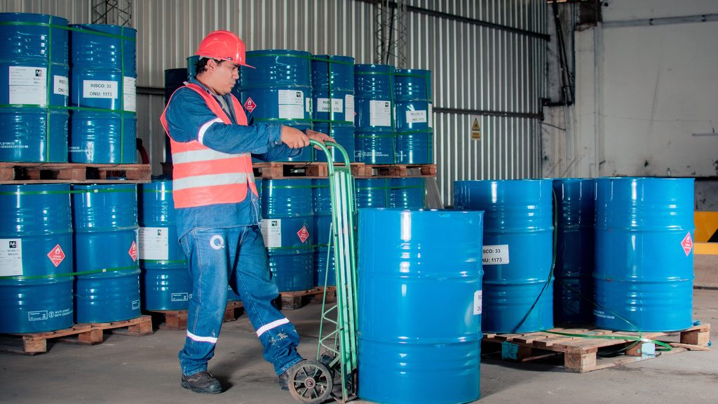 Operario moviendo bidones de producto químico en un almacén industrial