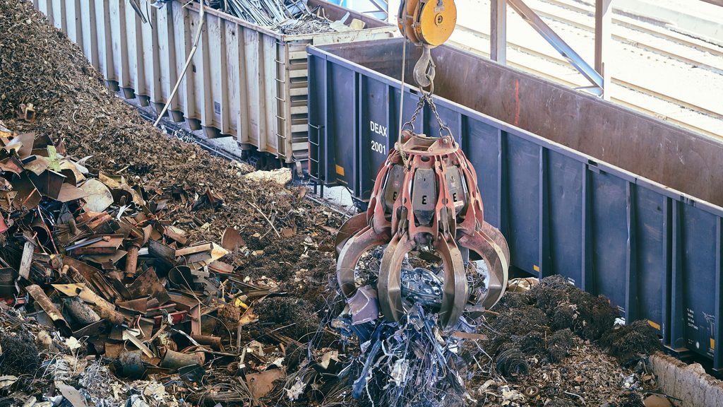 Pulpo hidráulico cargando residuos metálicos en el contenedor de un gestor autorizado
